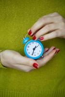 Little blue alarm clock in the hands of woman photo