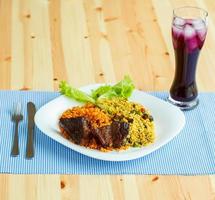 Dish of roast beef with rice and salad leaves and a glass of juice with ice photo