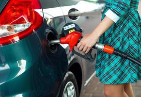 mujer llena gasolina dentro el coche a un gas estación foto