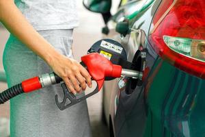 Woman fills petrol into the car at a gas station photo