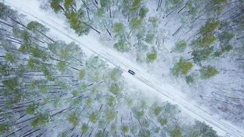 Aerial view on car driving through winter forest road. Scenic winter landscape photo