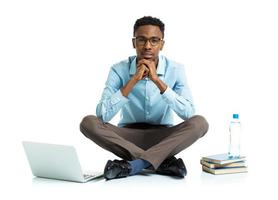 African american college student with laptop, books and bottle of water sitting on white photo