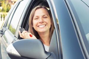 Young lady sitting in a car and showing key photo