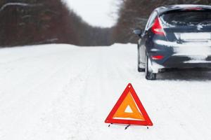 Closeup of red warning triangle with a broken down car photo