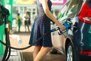 mujer llena gasolina dentro el coche a un gas estación foto