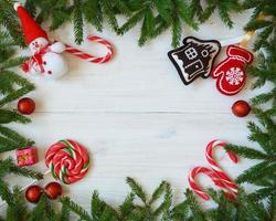 Navidad frontera con abeto árbol sucursales, Navidad decoraciones y caramelo caña en blanco de madera tableros foto