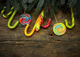 Christmas border with fir tree branches, pine cones and candy cane on rustic wooden boards photo