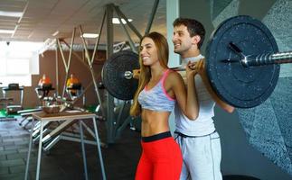 atlético Pareja con barra con pesas haciendo ejercicios en el gimnasio foto