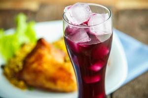 Tasty dish of chicken thigh with rice and lettuce and a glass of juice with ice photo