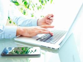 Hands or men office worker typing on the keyboard and using smartphone photo