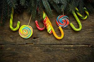 Christmas border with fir tree branches, pine cones and candy cane on rustic wooden boards photo