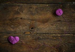 Purple Heart with a ball of thread on on old shabby wooden background photo