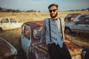 joven hermoso elegante hombre, vistiendo camisa y corbata de moño con antiguo carros foto