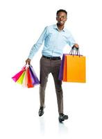 Happy african american man holding shopping bags on white. Holidays concept photo