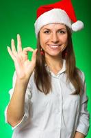 Girl in a Christmas hat on a green background photo