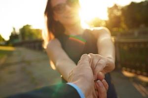 Follow me - happy young woman pulling guy's hand - hand in hand walking on a bright sunny day photo