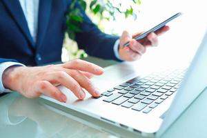 Men office worker typing on the keyboard and using smartphone photo