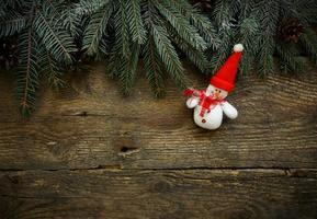 Christmas tree branches with snowman on wooden texture photo