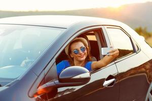 mujer en sombrero y Gafas de sol haciendo yo retrato sentado en el coche foto