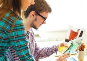 Young colleague - manand woman looking to a color paint palette at home office photo