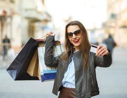 hermosa mujer con compras pantalones y crédito tarjeta en el manos en un calle foto