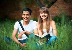 Two students guy and girl studying in park on grass with book photo