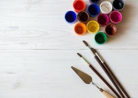Watercolors and paint brush on white wooden background photo