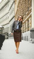 Businesswoman walking down the street while talking on smart phone photo