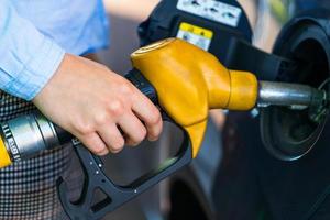 Woman fills petrol into the car at a gas station photo