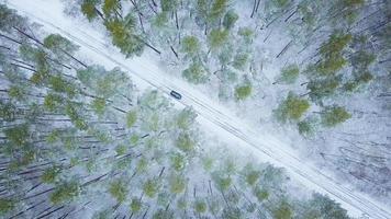 Aerial view on car driving through winter forest road. Scenic winter landscape photo