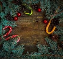 Christmas border with fir tree, cones, christmas decorations and candy cane on wooden boards photo