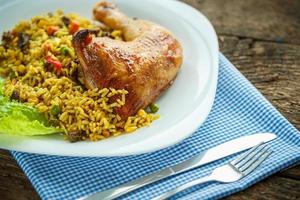 Delicious dish of chicken thigh with rice and salad leaves photo