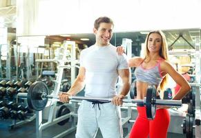 Athletic couple with barbell doing exercises in the gym photo