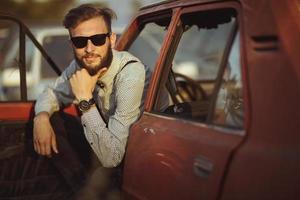 joven hermoso elegante hombre, vistiendo camisa y corbata de moño con antiguo carros foto