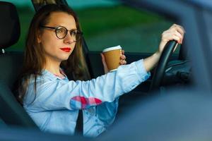 joven mujer con café a Vamos conducción su coche foto