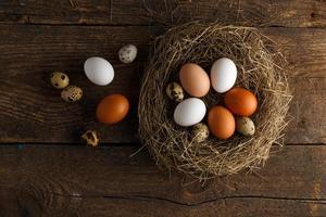 Chicken and quail eggs in a nest on a wooden rustic background photo