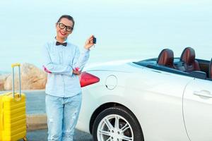 Young woman standing near a convertible with keys in hand photo