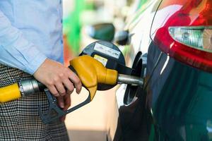 mujer llena gasolina dentro el coche a un gas estación foto