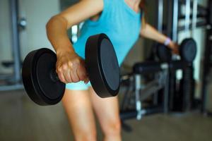 Woman with dumbbells in the gym doing sport exercises photo