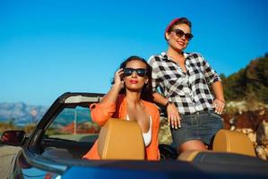 dos joven muchachas teniendo divertido en el cabriolé al aire libre foto