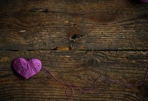 Purple Heart with a ball of thread on on old shabby wooden background photo