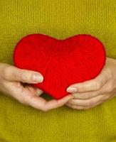 Closeup on red heart made from wool in hand of woman photo