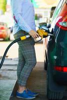 mujer llena gasolina dentro el coche a un gas estación foto