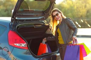 Caucasian woman putting her shopping bags into the car trunk photo