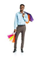 Happy african american man holding shopping bags on white. Holidays concept photo