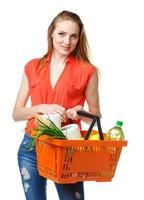 Happy young woman holding a basket full of healthy food on white. Shopping photo