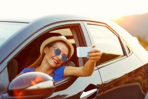 Woman in hat and sunglasses making self portrait sitting in the car photo