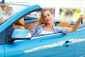 joven bonito mujer sentado en un convertible coche con el llaves en mano foto