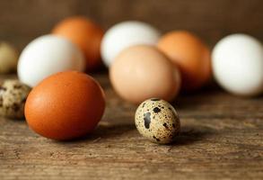 Chicken and quail eggs on a wooden rustic background photo