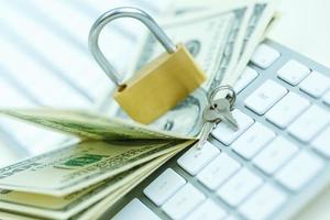 Security lock on dollar bills with white computer keyboard photo